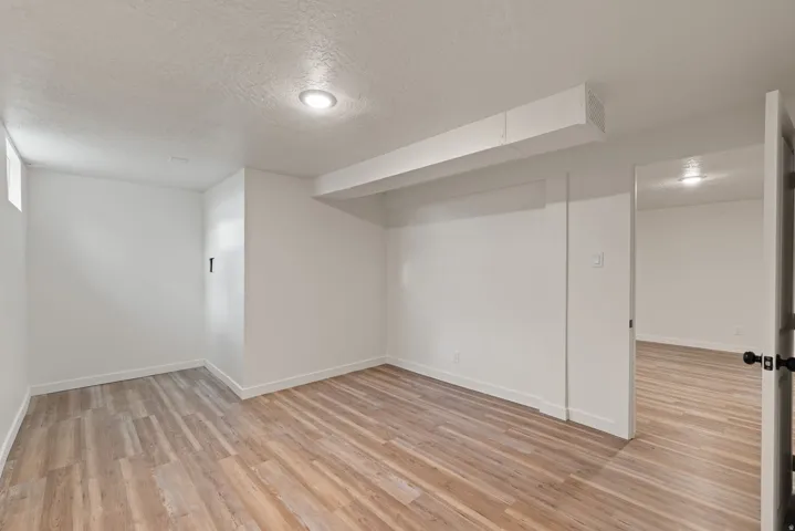 Finished basement with a textured ceiling and light wood finished floors