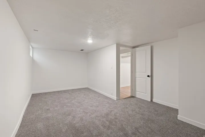 Finished basement with a textured ceiling and light carpet