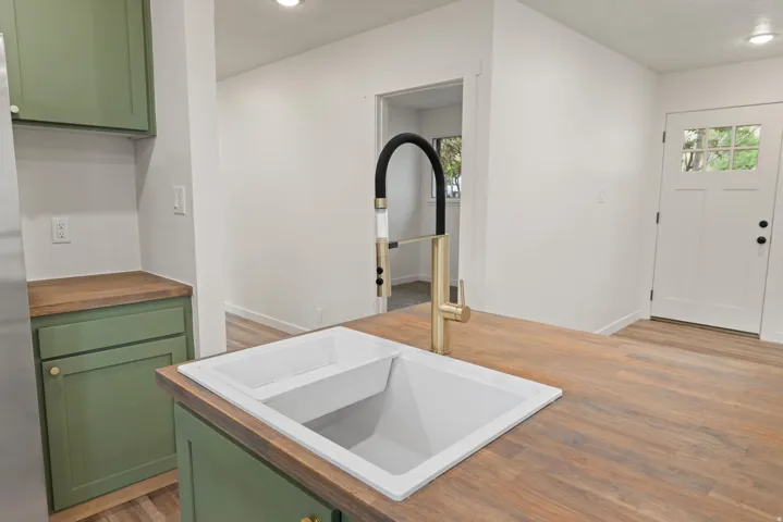 Kitchen featuring green cabinets, light wood finished floors, wooden counters, freestanding refrigerator, and recessed lighting