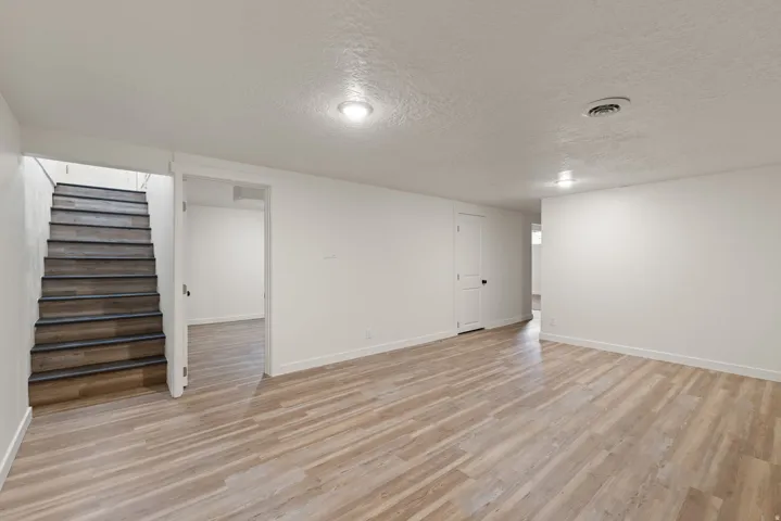 Finished basement featuring a textured ceiling and light wood-style floors