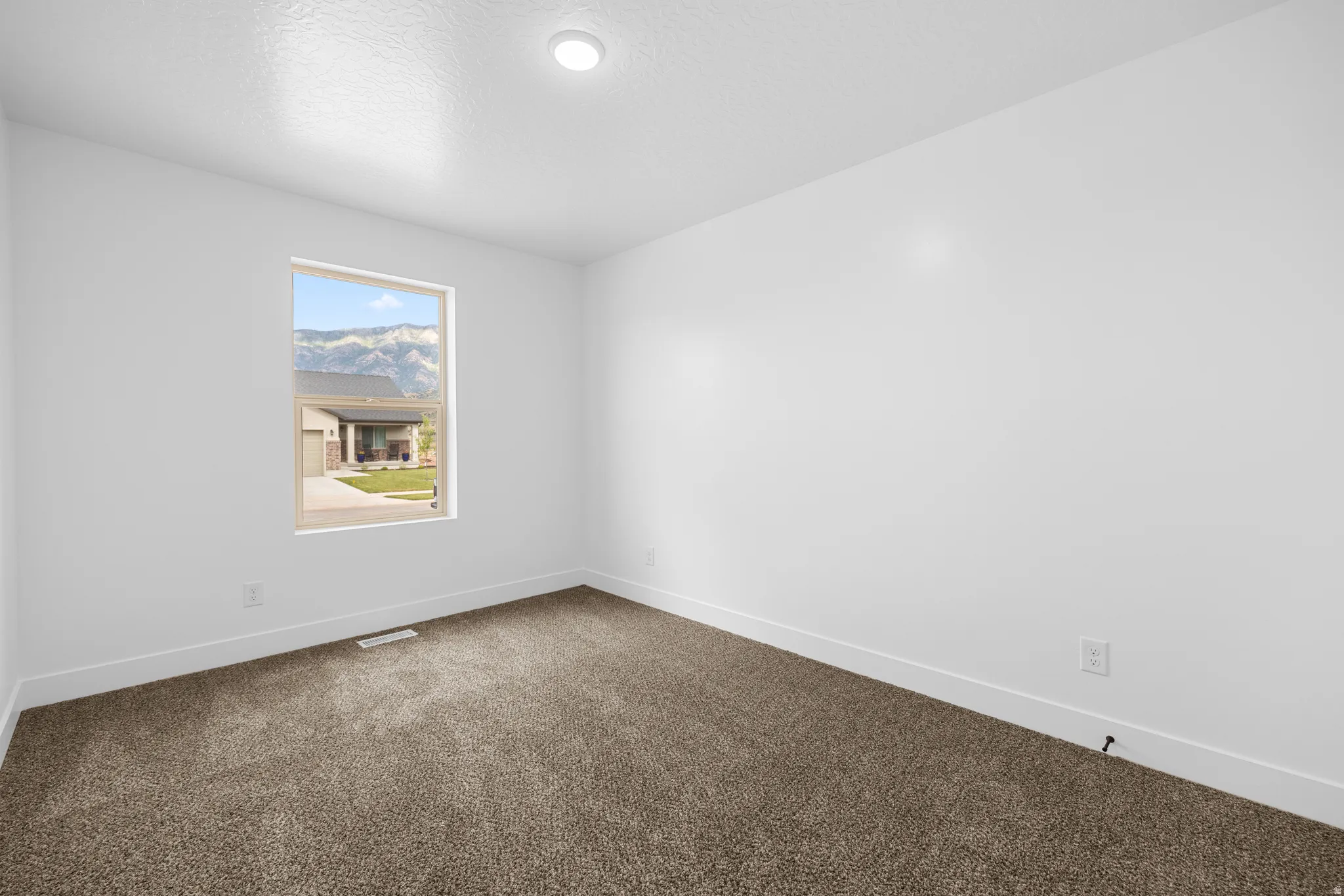 Spare room with dark carpet and a textured ceiling
