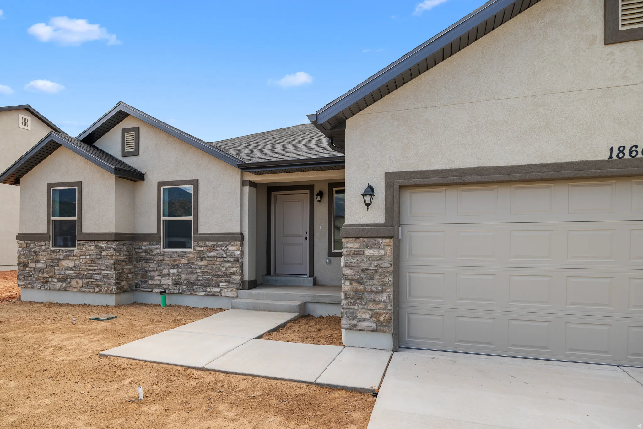 View of front of property featuring stucco siding, stone siding, roof with shingles, and driveway