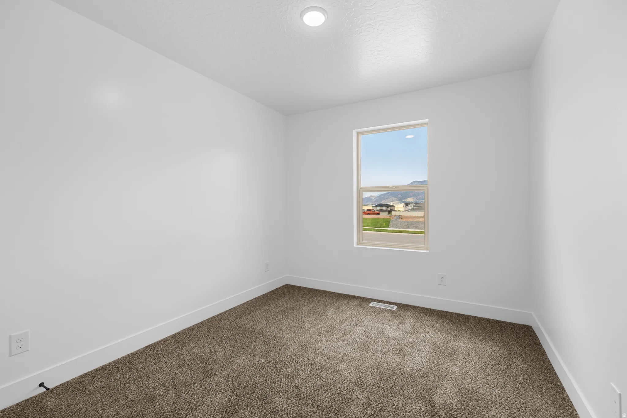 Spare room featuring dark colored carpet, a textured ceiling, and a mountain view