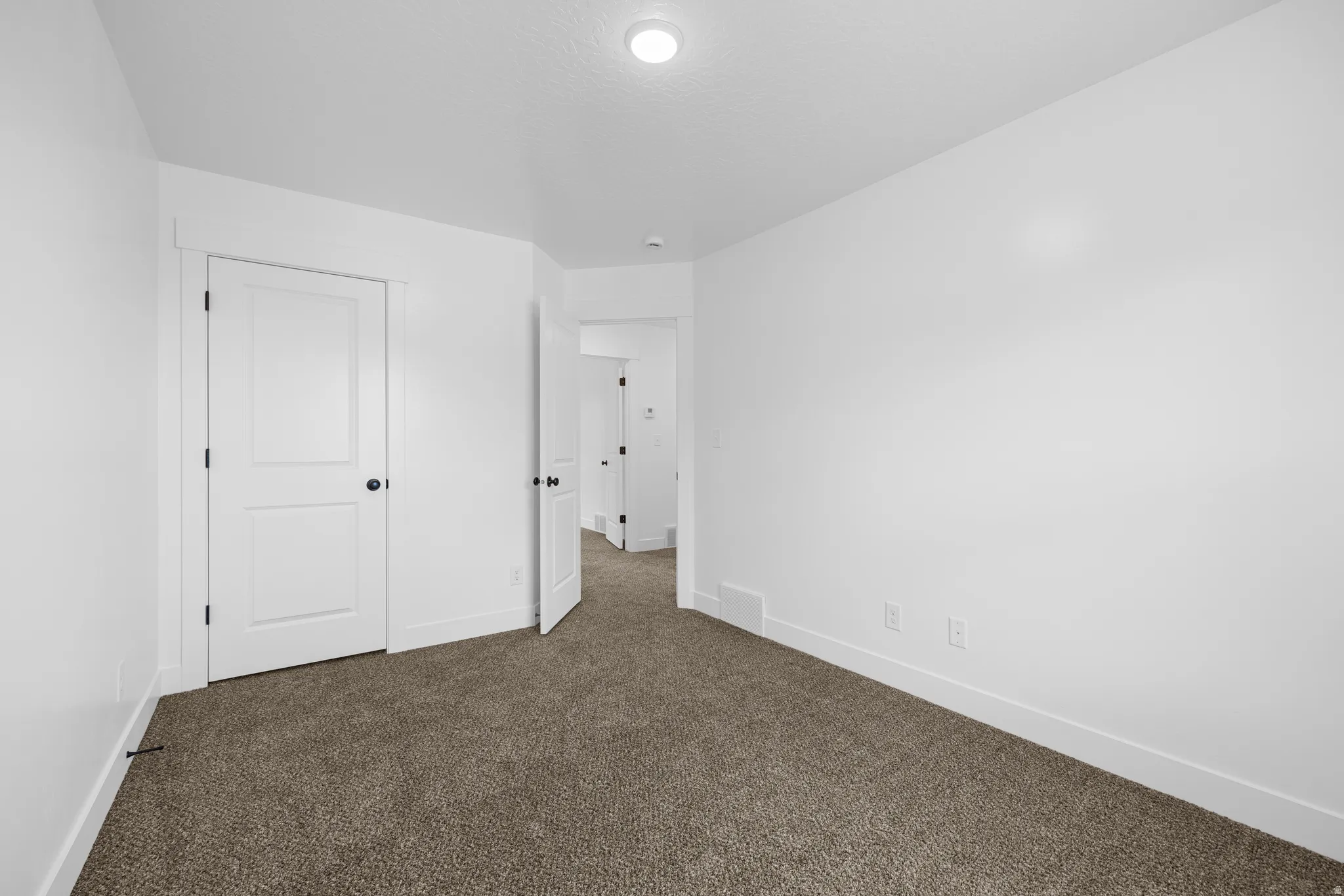 Unfurnished bedroom with dark carpet and baseboards