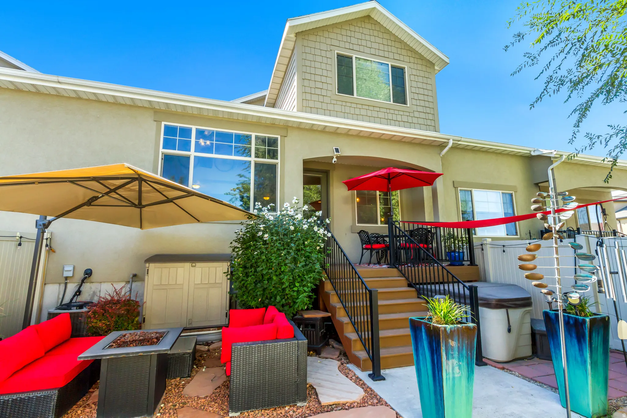 View of front facade featuring a patio, stucco siding, an outdoor living space with a fire pit, and a deck