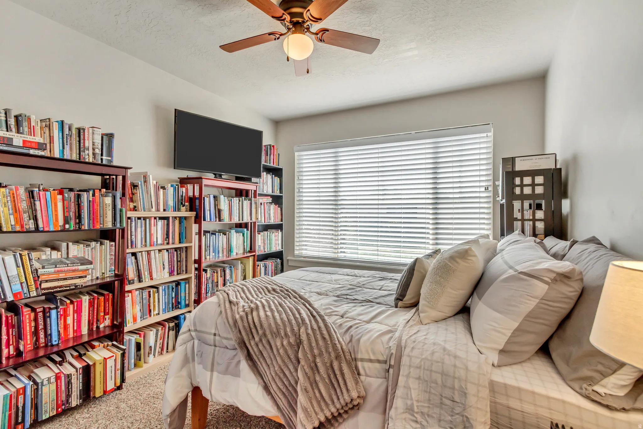 Carpeted bedroom with ceiling fan and a textured ceiling