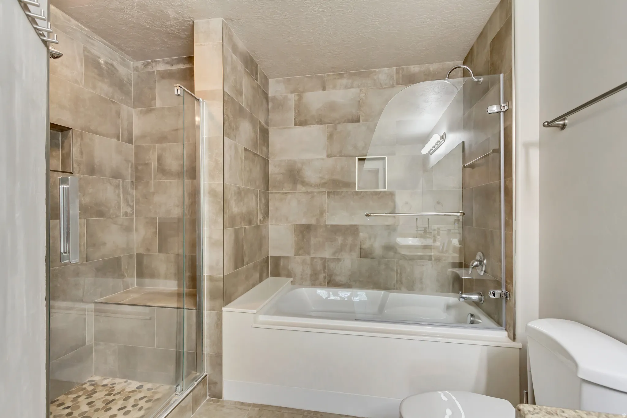 Full bathroom with a stall shower, a bath, and a textured ceiling