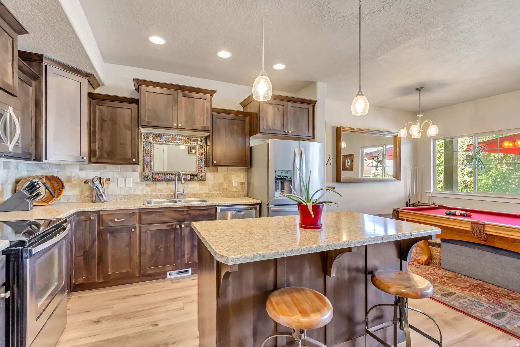 Kitchen with a kitchen breakfast bar, stainless steel appliances, light wood-type flooring, a center island, and dark wood finish cabinets