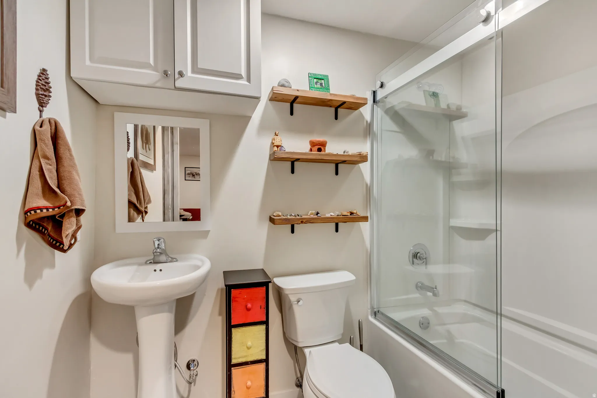 Full bathroom featuring toilet and shower / bath combination with glass door