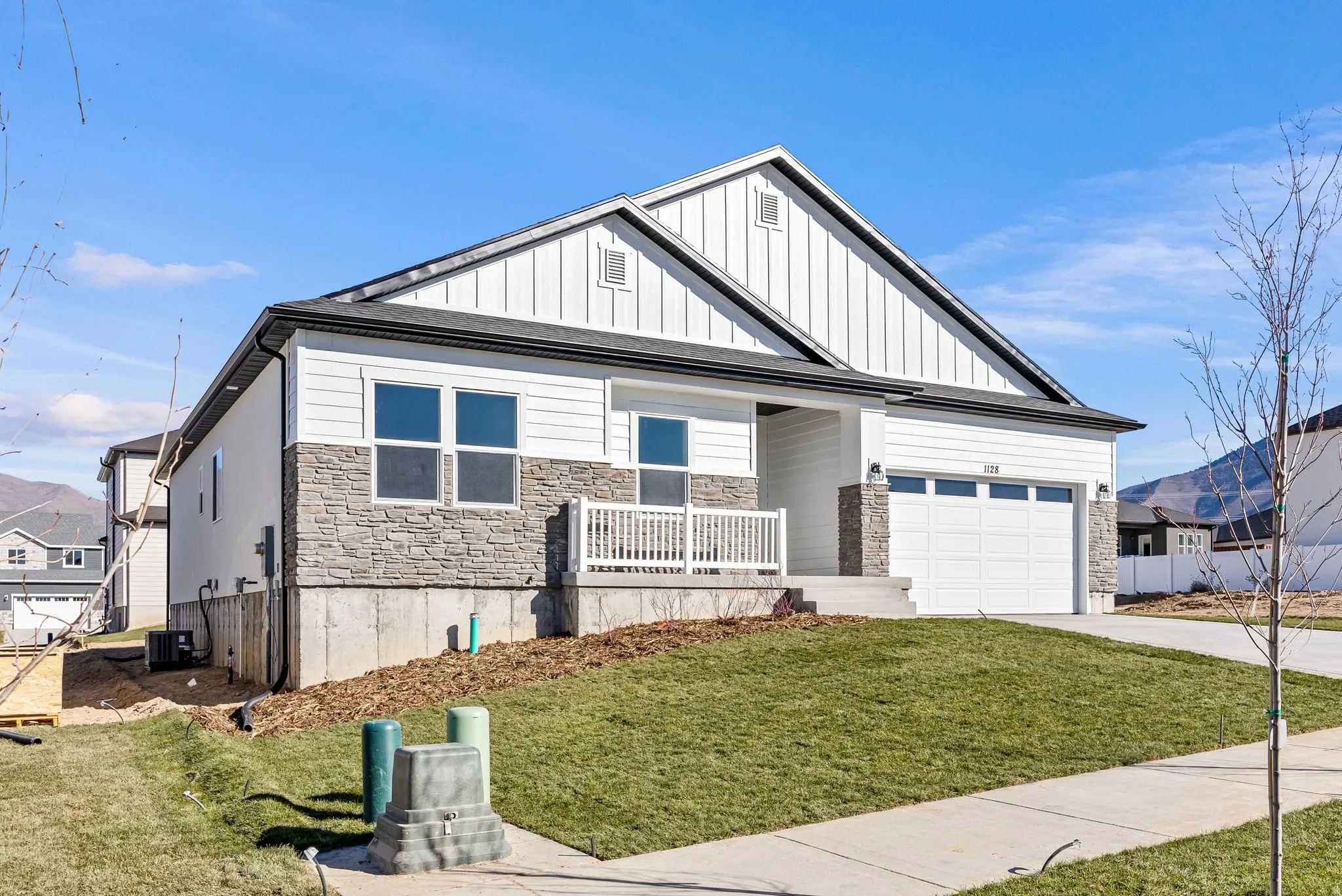View of front facade featuring concrete driveway, a garage, stone siding, a porch, and board and batten siding