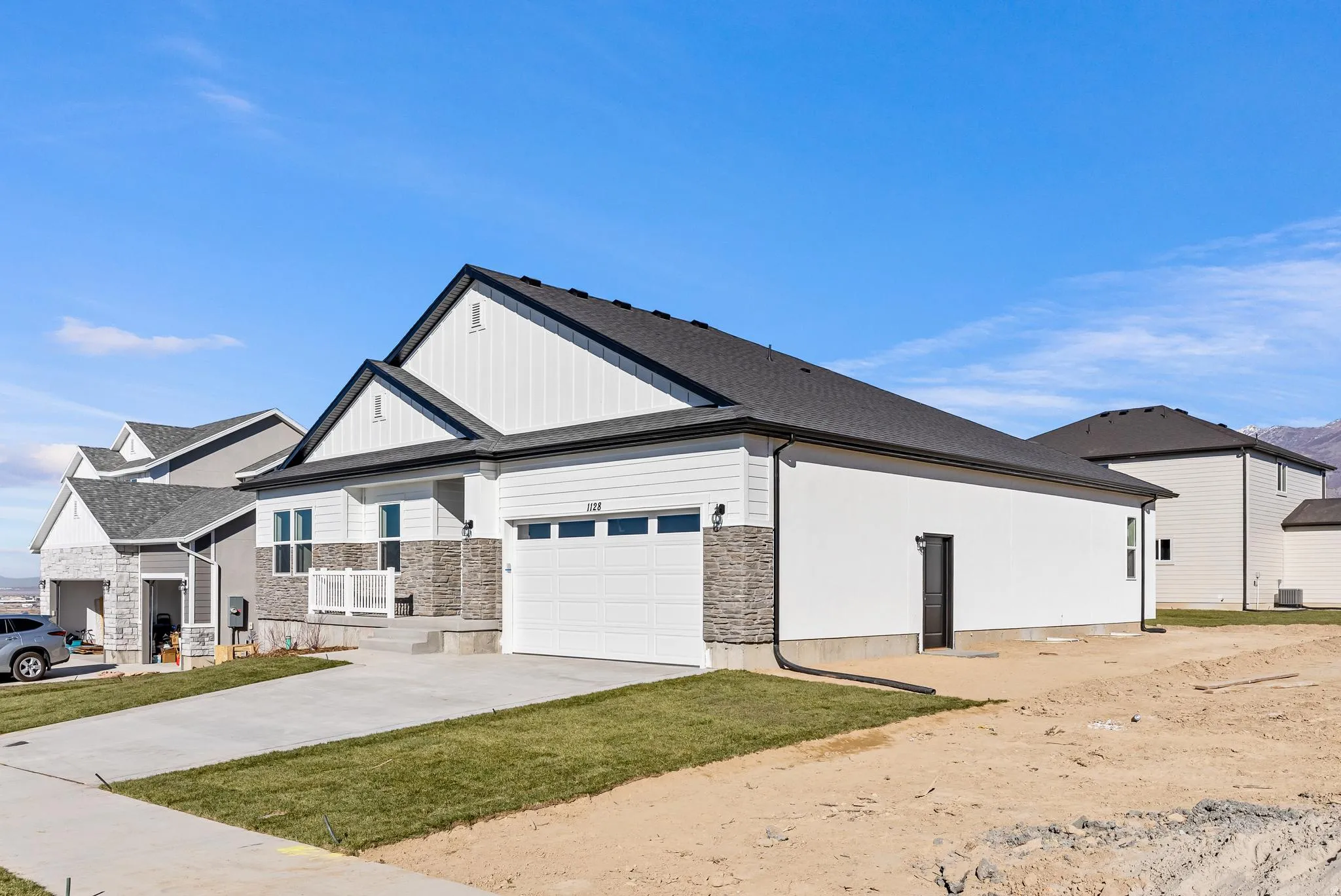 View of property exterior with stone siding, concrete driveway, a garage, and board and batten siding