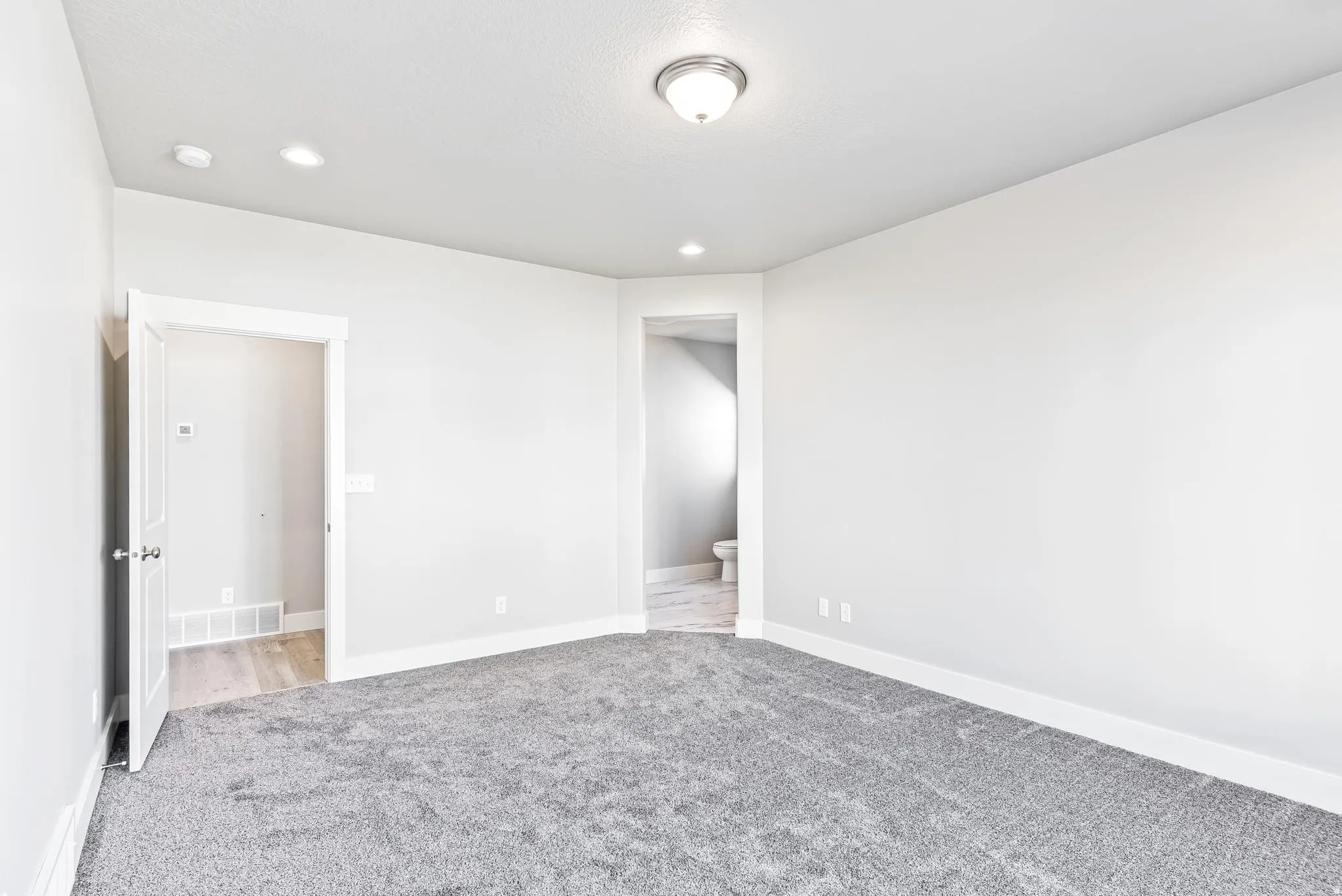 Unfurnished bedroom with light colored carpet and recessed lighting