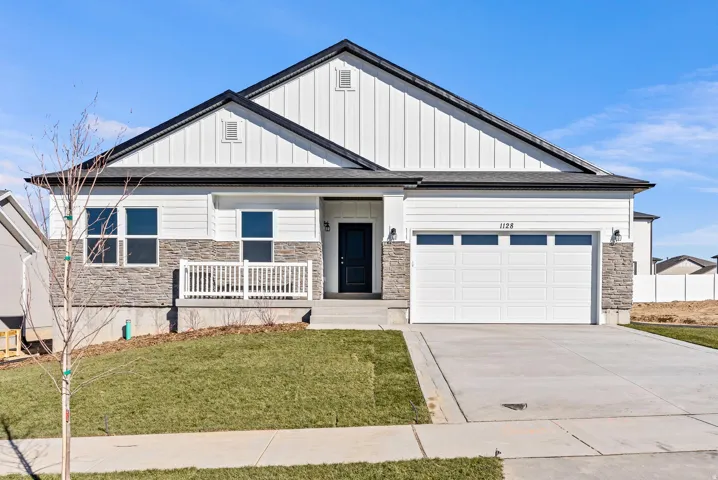 View of front of home featuring stone siding, board and batten siding, a front lawn, concrete driveway, and a garage