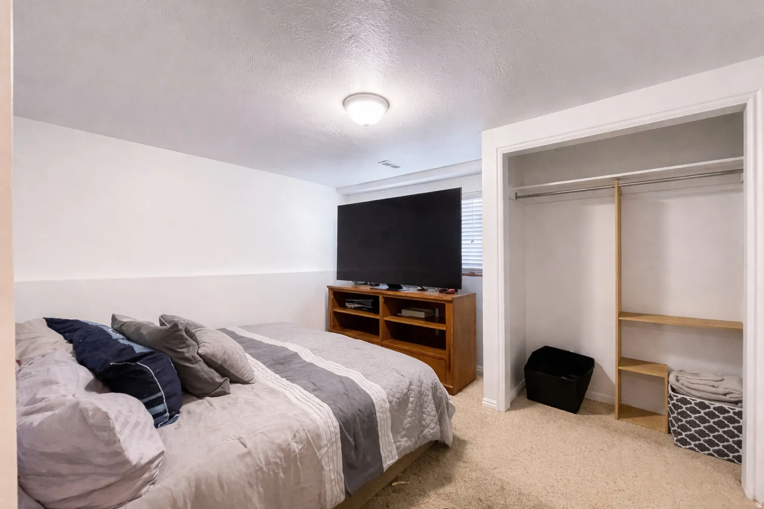 Bedroom featuring light carpet, a textured ceiling, and a closet
