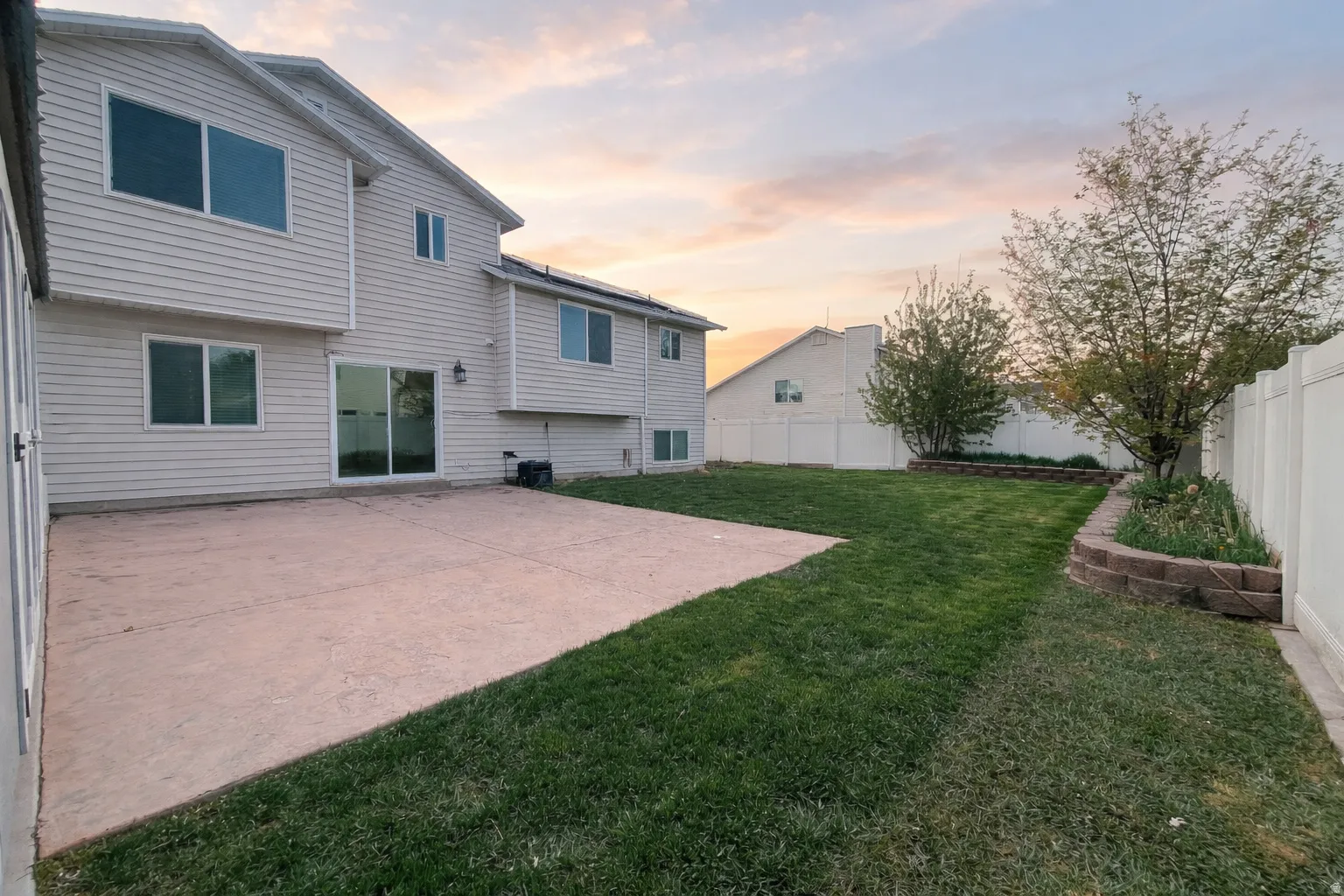 Back of property at dusk with a patio area and a fenced backyard