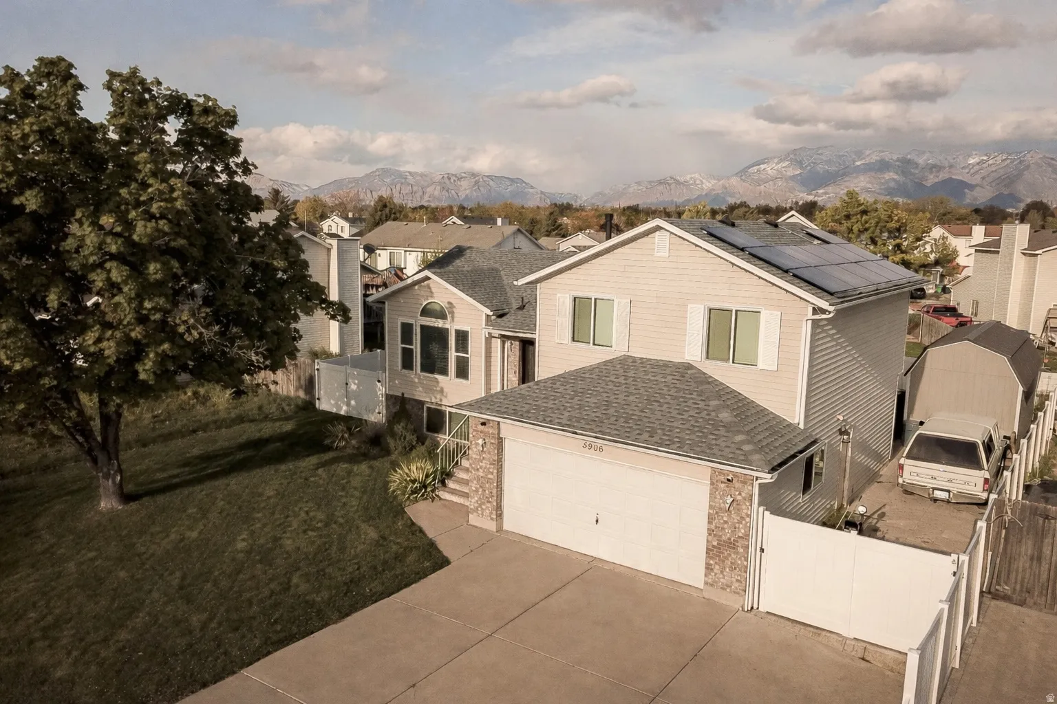 View of front facade with a gate, a residential view, solar panels, driveway, and brick siding