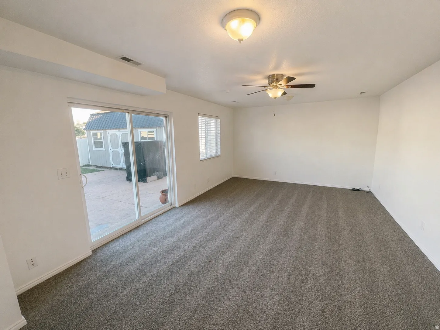 Carpeted empty room featuring baseboards and ceiling fan