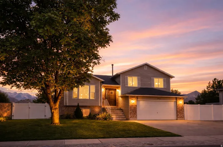 Split level home with a gate, brick siding, concrete driveway, and a garage