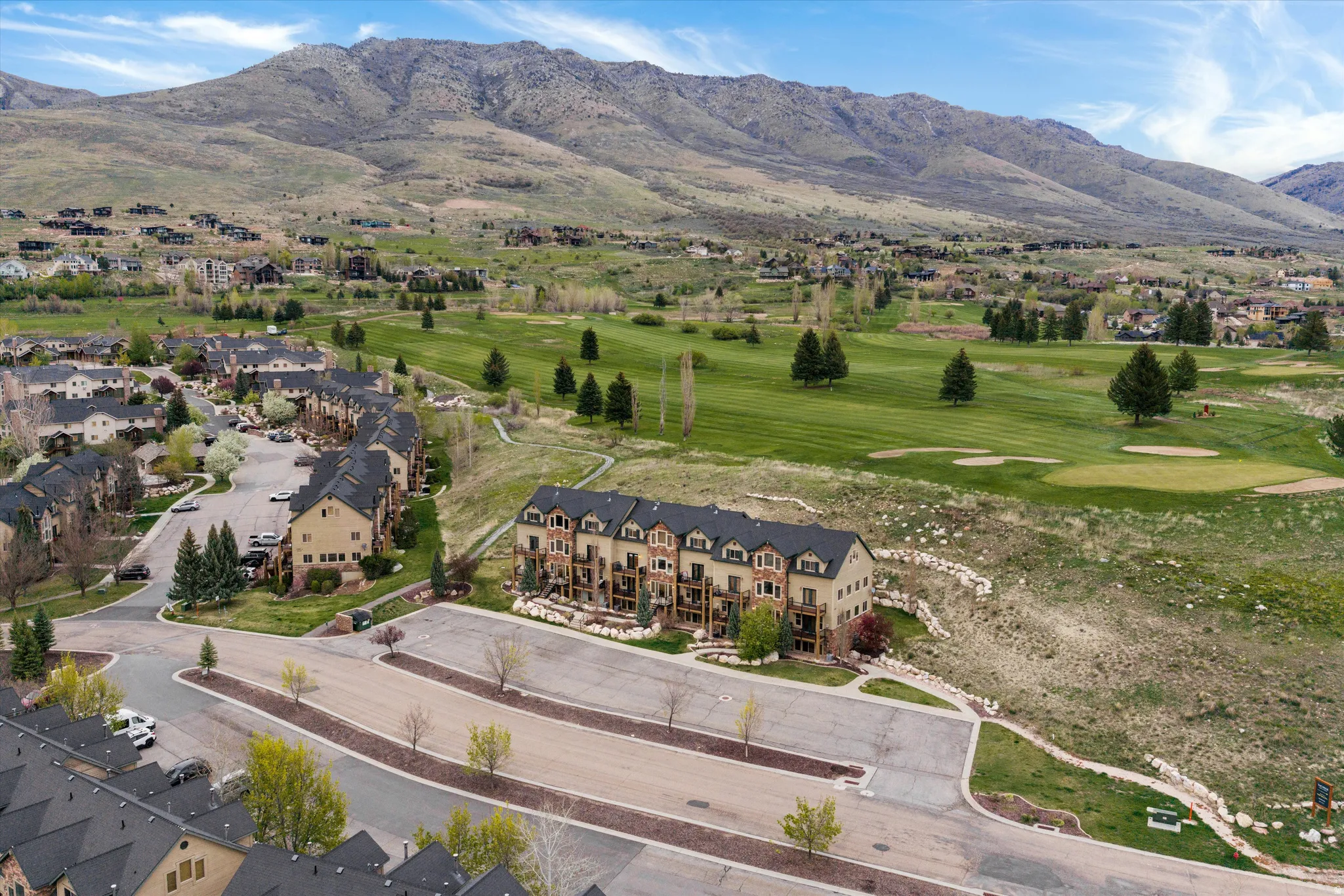 Aerial perspective of suburban area featuring a mountainous background and a local golf course