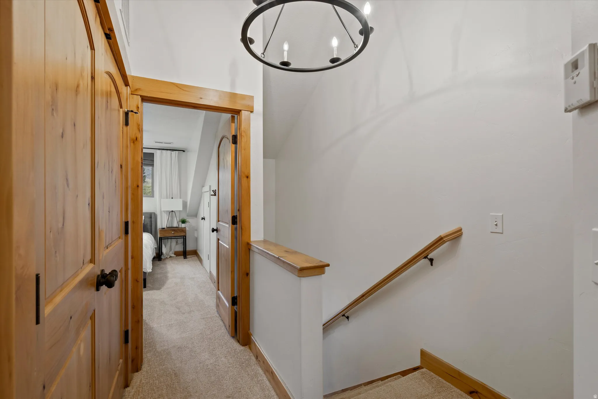 Hall featuring light colored carpet and a chandelier