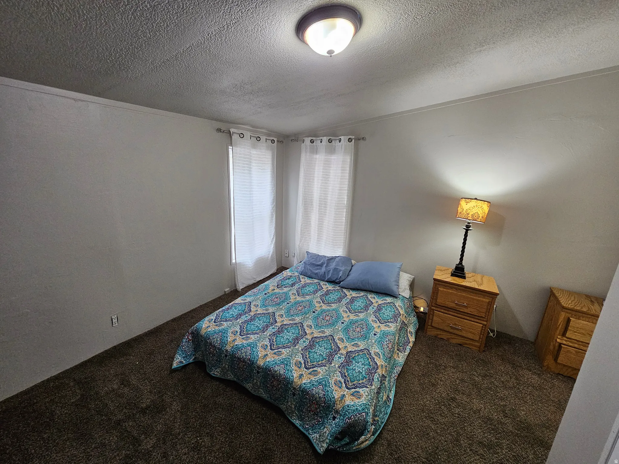 Bedroom with dark carpet and a textured ceiling
