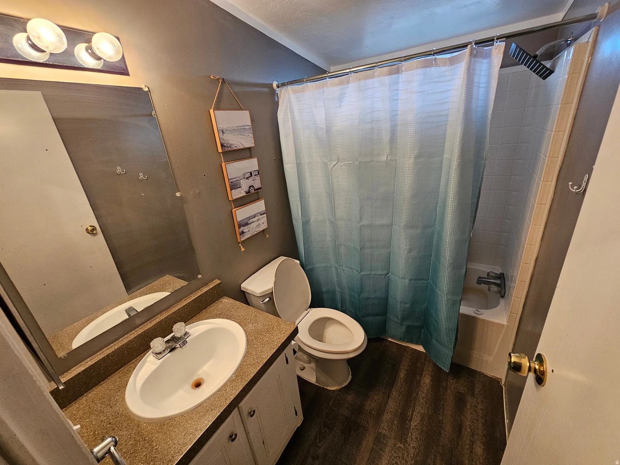 Full bathroom featuring shower / tub combo with curtain, vanity, and dark wood-type flooring