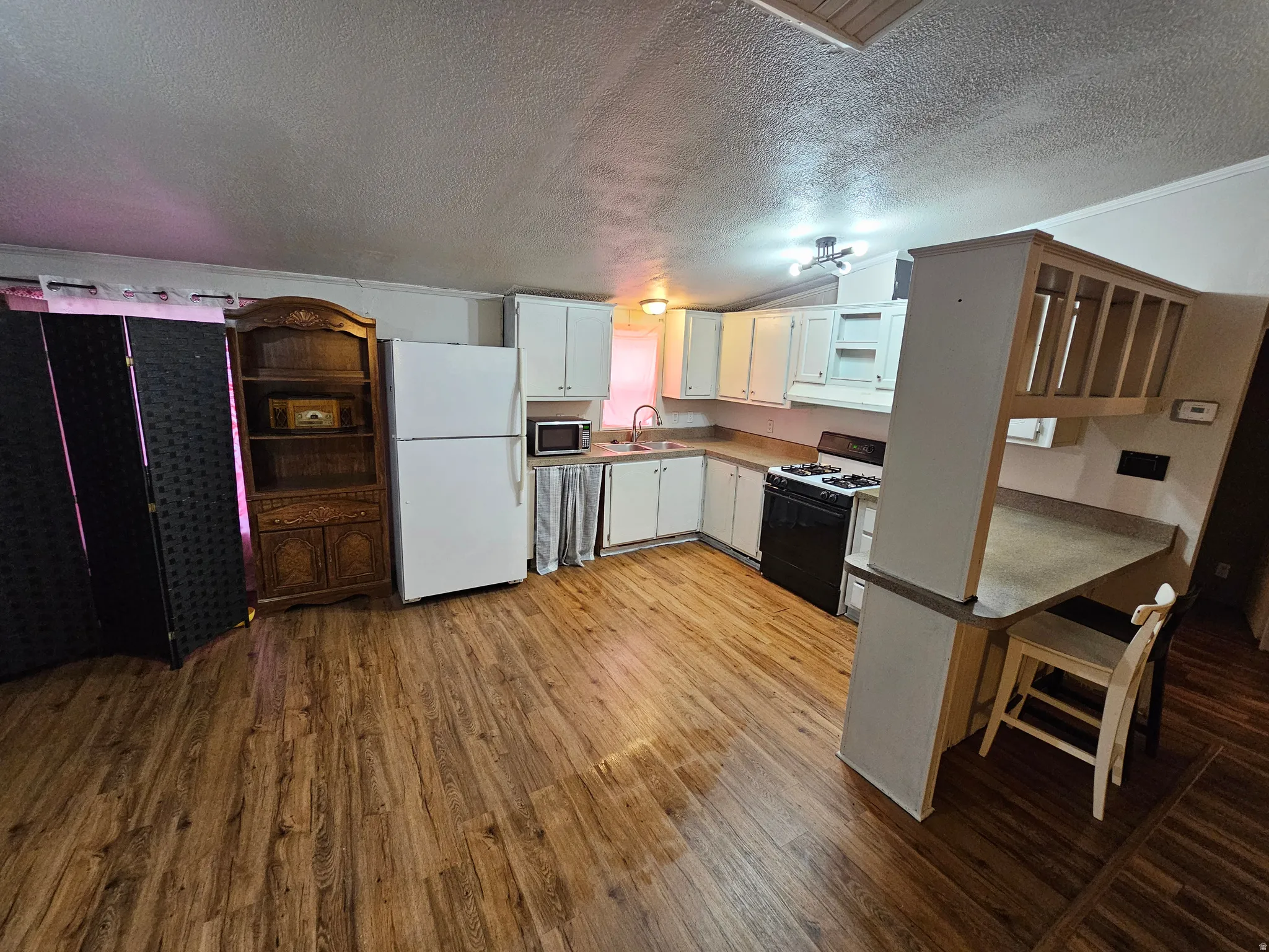 Kitchen featuring freestanding refrigerator, range with gas cooktop, light wood-style floors, white cabinets, and open shelves
