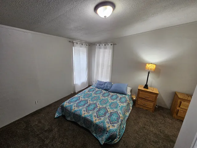 Bedroom with dark carpet and a textured ceiling