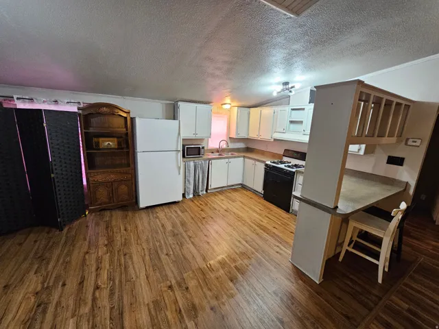 Kitchen featuring freestanding refrigerator, range with gas cooktop, light wood-style floors, white cabinets, and open shelves