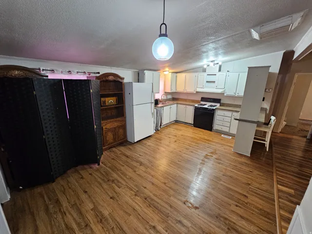 Kitchen with freestanding refrigerator, range with gas stovetop, decorative light fixtures, fridge, and light wood-style flooring