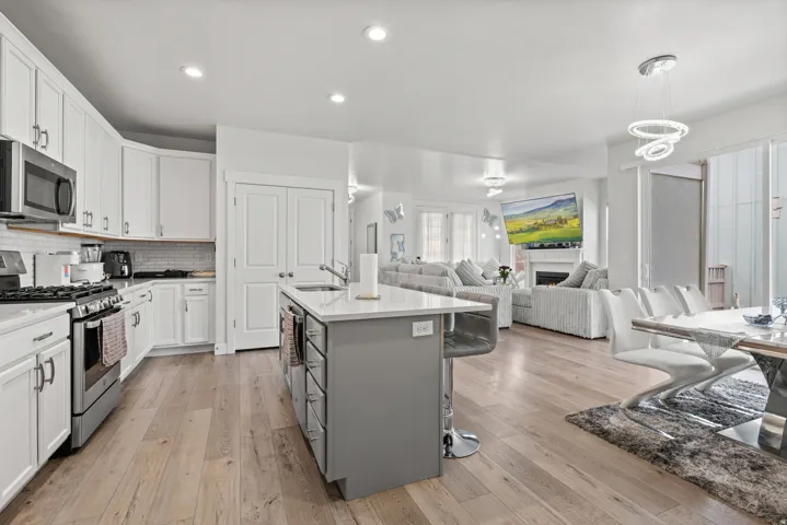 Kitchen featuring stainless steel appliances, two tone cabinets, a fireplace, light stone countertops, and open floor plan