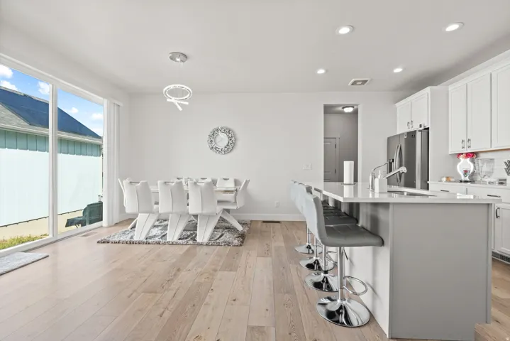 Kitchen with white cabinetry, light wood-type flooring, and stainless steel fridge with ice dispenser