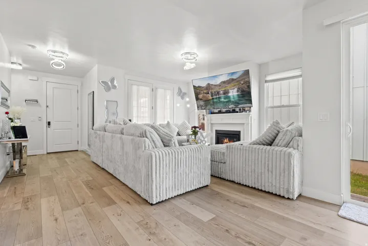 Living room with light wood-style flooring and a warm lit fireplace