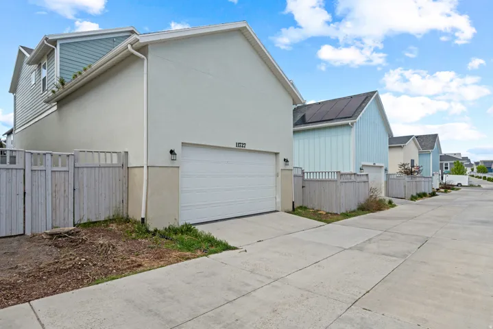 View of side of property with a gate, driveway, stucco siding, and a residential view