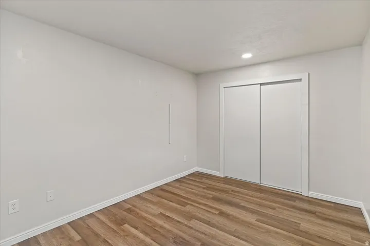 Bedroom with light wood-type flooring, a closet, and recessed lighting