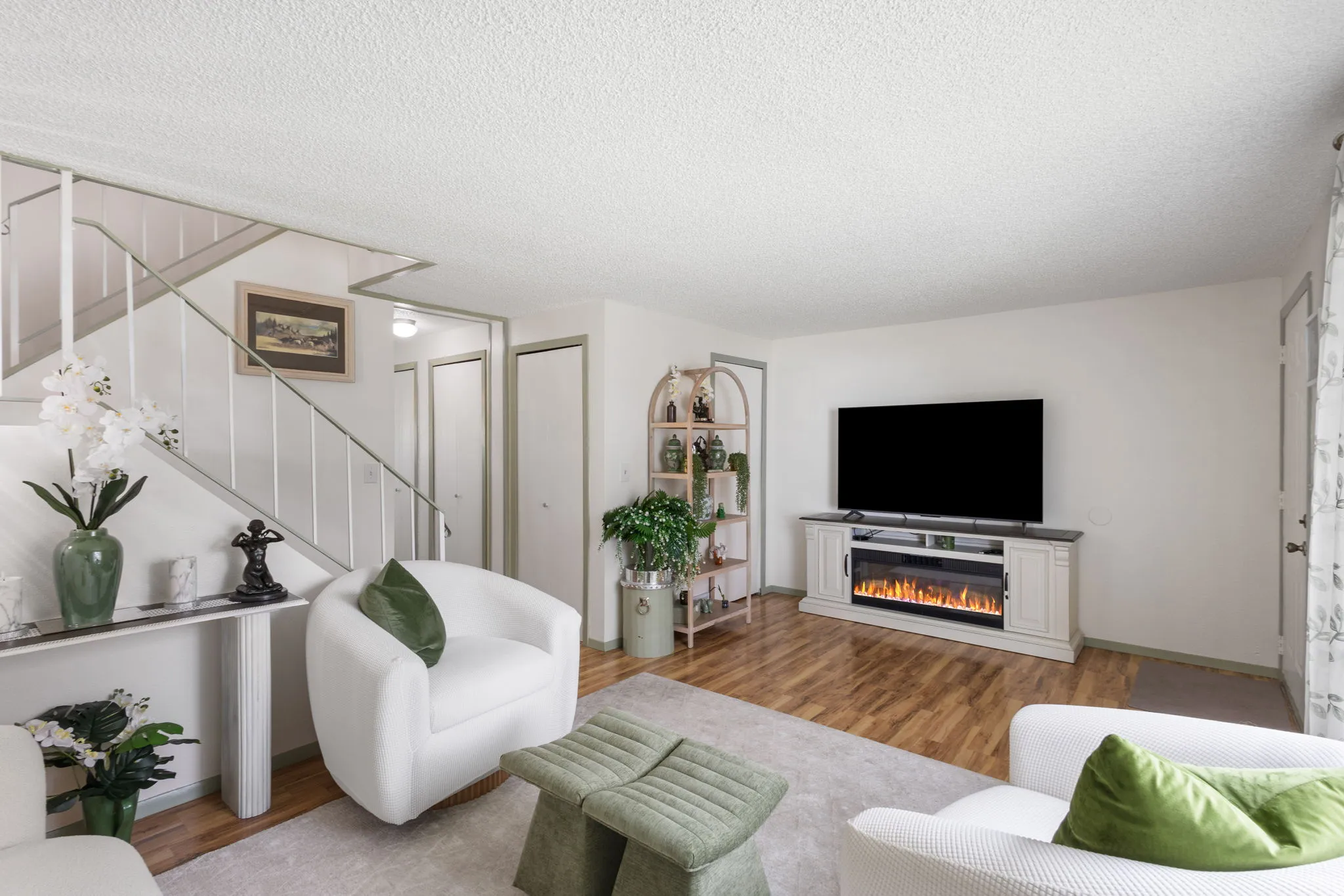 Living room featuring light wood finished floors, a textured ceiling, and a glass covered fireplace