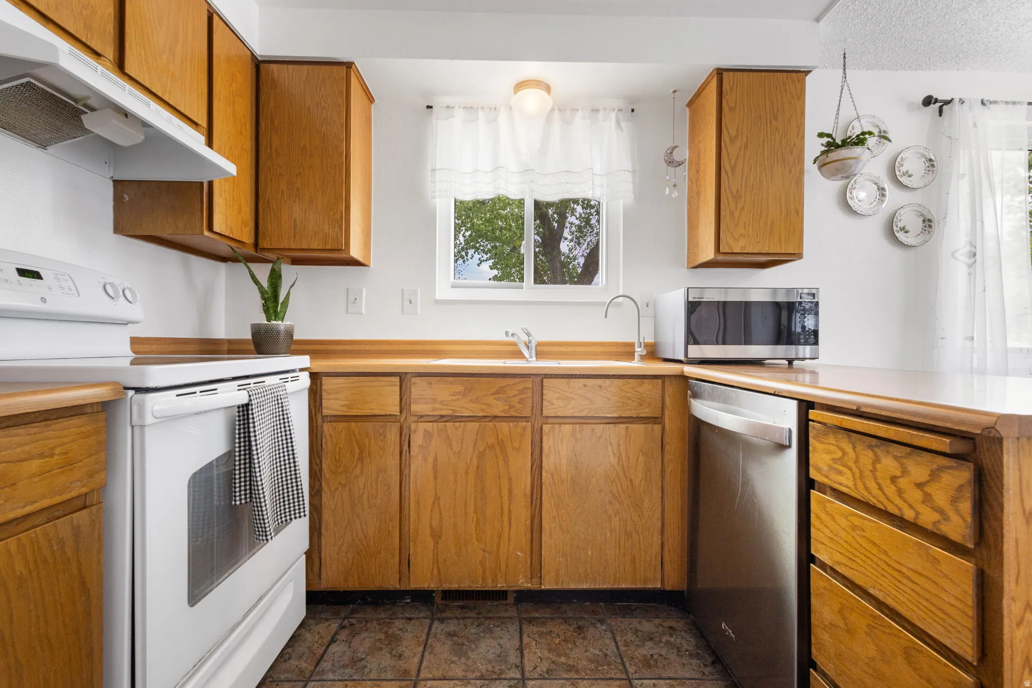 Kitchen featuring wood finish cabinetry, stainless steel appliances, light countertops, and healthy amount of natural light