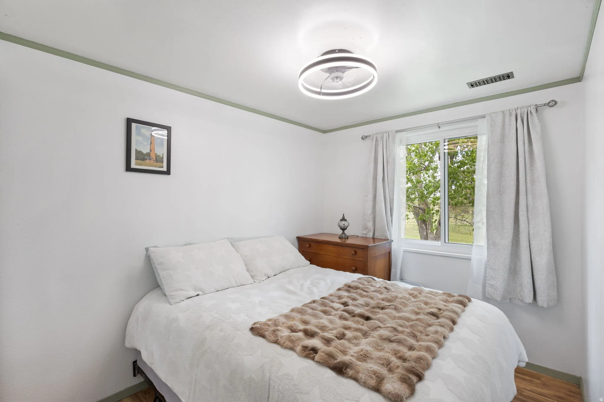 Bedroom with wood finished floors and crown molding