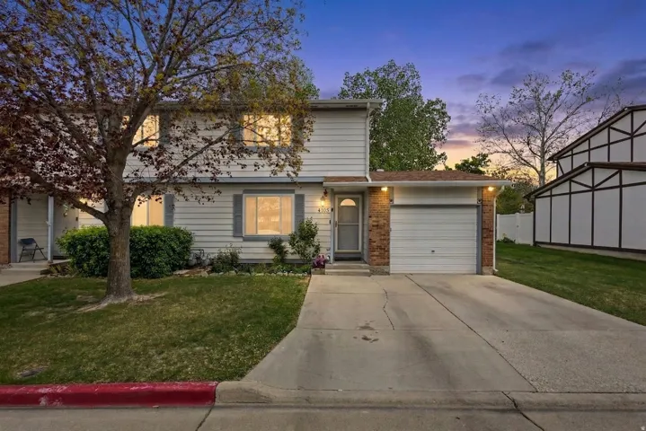 View of front of home with an attached garage, a front yard, brick siding, and driveway