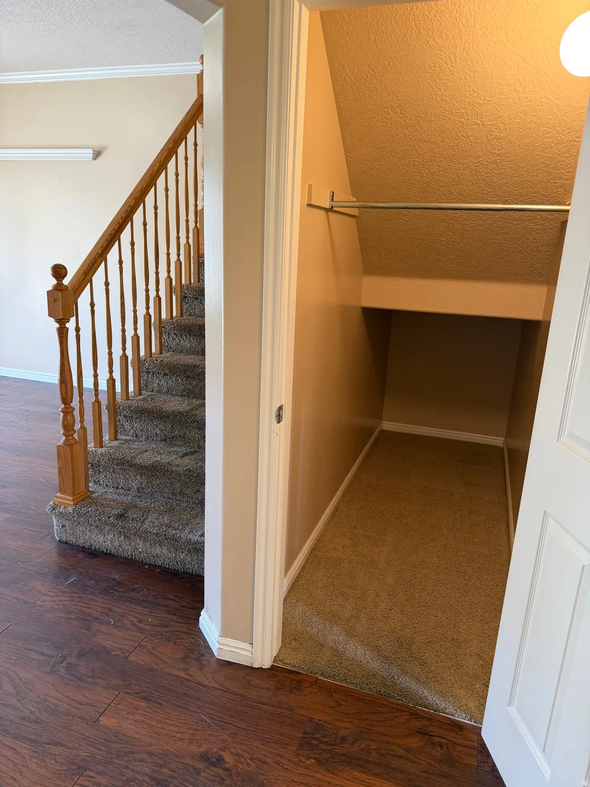 Staircase with a textured ceiling, wood-type flooring, and crown molding