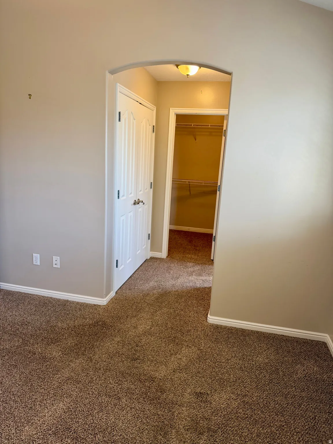 Hallway featuring arched walkways and dark carpet