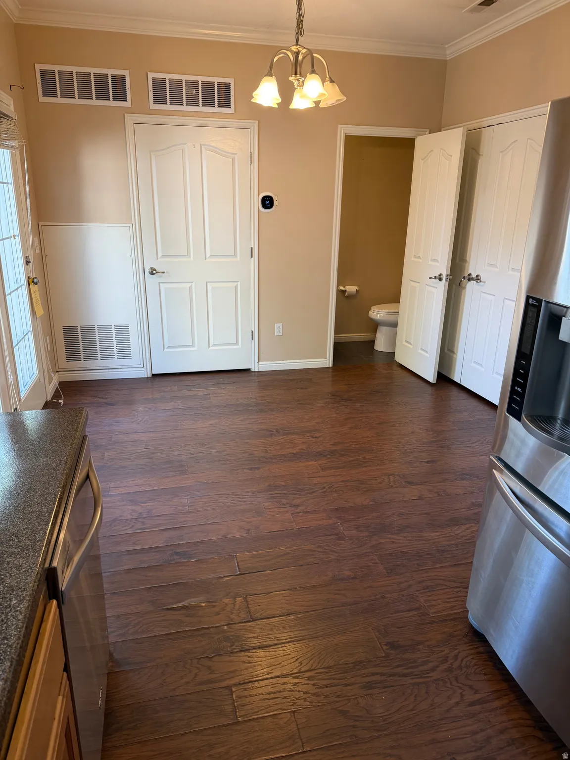 Unfurnished dining area featuring ornamental molding, suspended lighting, and dark wood-style flooring