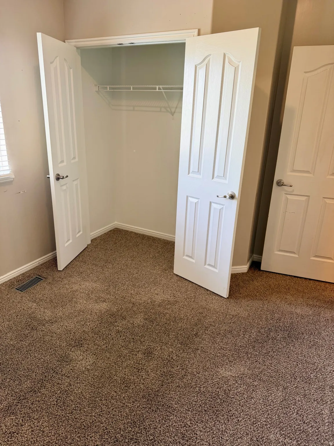 Unfurnished bedroom with dark colored carpet and baseboards