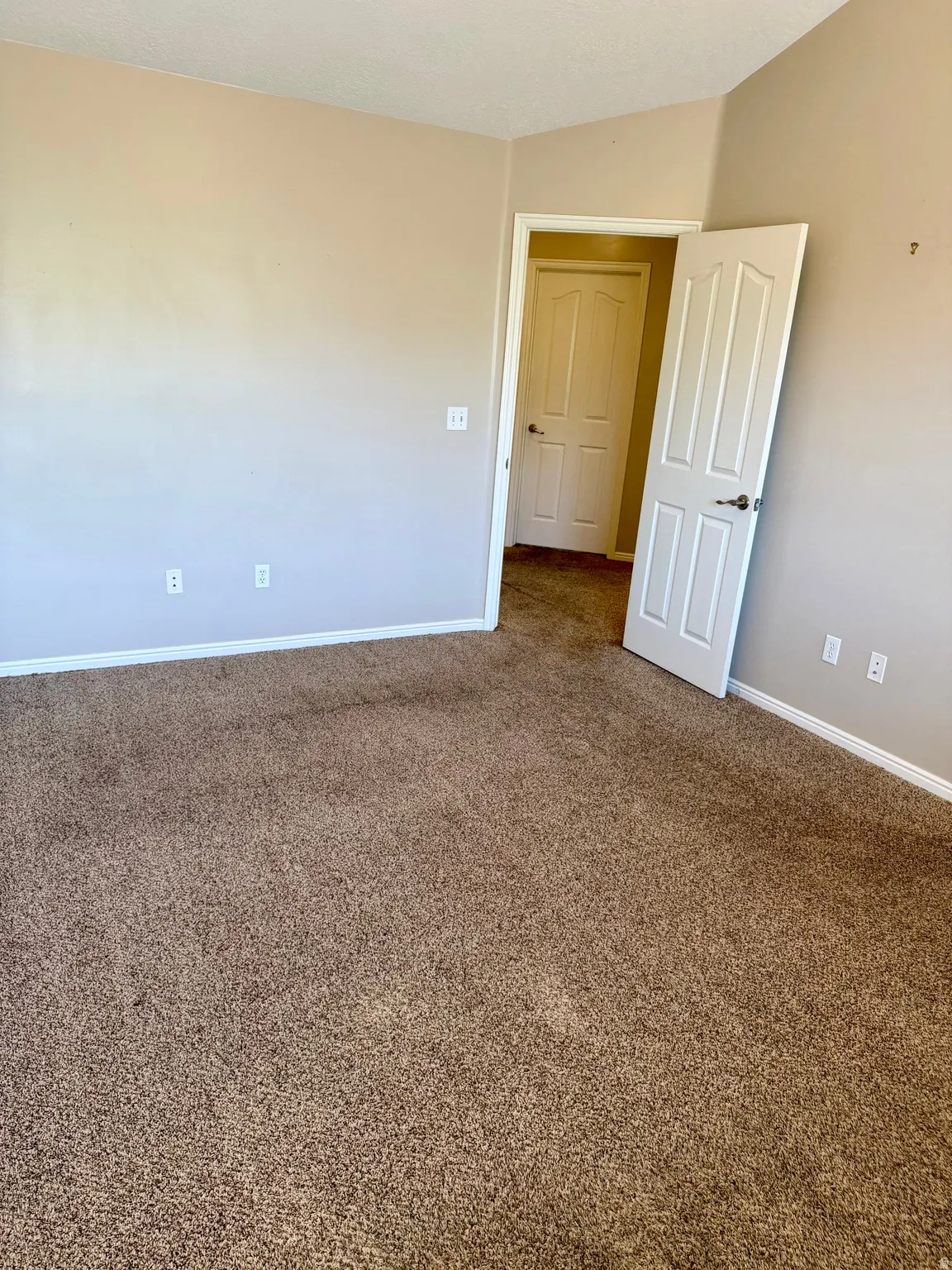 Spare room with dark carpet and baseboards