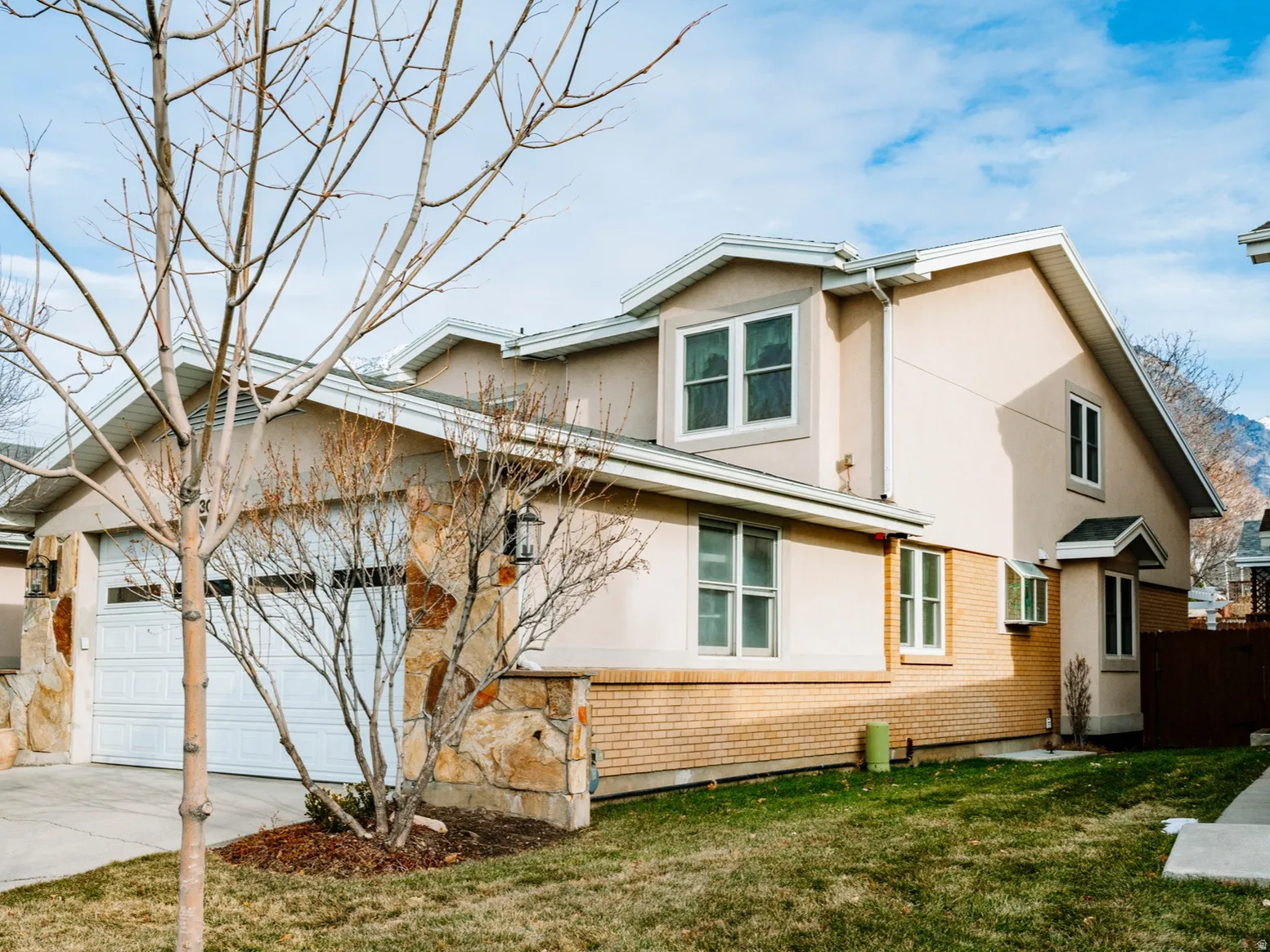 View of front of property featuring stucco siding, a front yard, concrete driveway, brick siding, and an attached garage