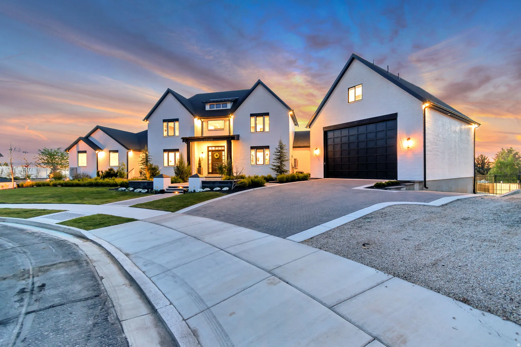 Modern farmhouse with driveway, an outbuilding, stucco siding, and a front lawn