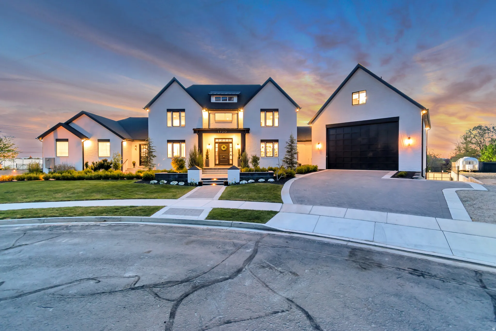 Modern farmhouse style home featuring a yard, driveway, stucco siding, and a garage