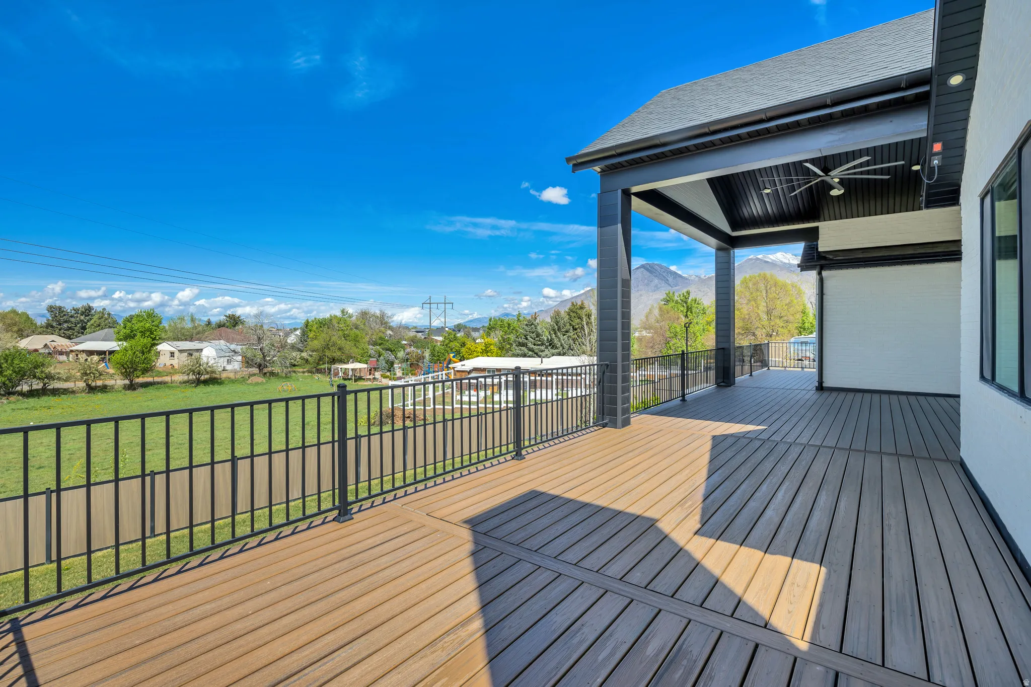 Wooden terrace with a lawn, a ceiling fan, a residential view, and a mountain view