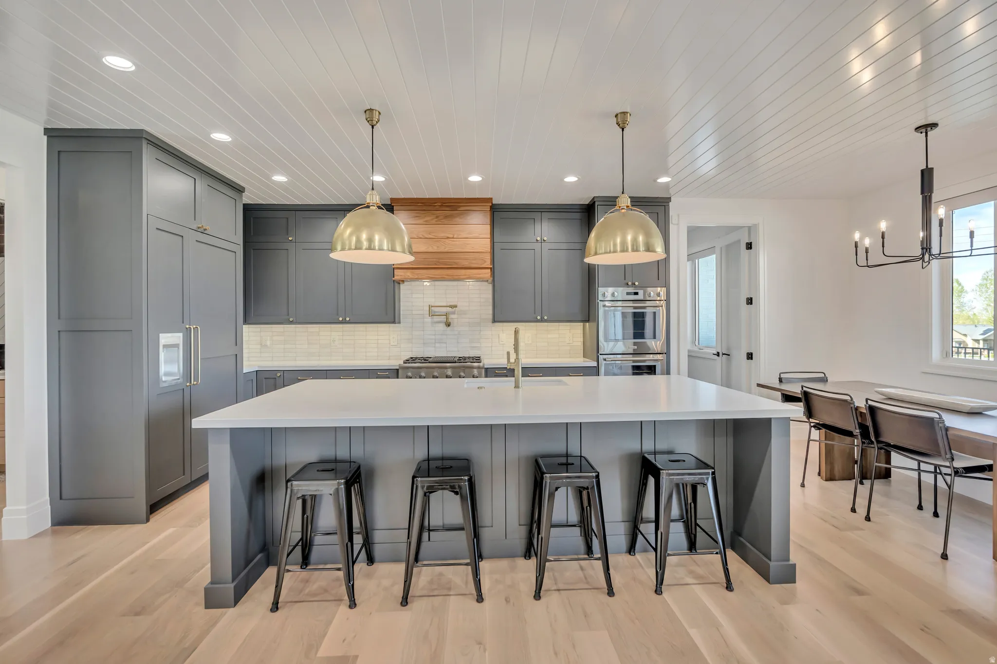 Kitchen with gray cabinets, a breakfast bar area, a large island, light wood-type flooring, and stainless steel double oven