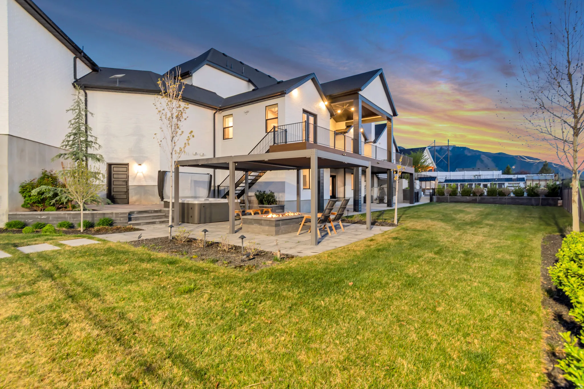 Back of property at dusk featuring a patio, a mountain view, a hot tub, and a balcony